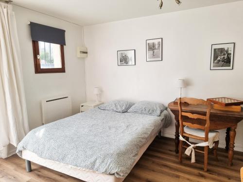 Schlafzimmer mit einem Bett und einem Holzschreibtisch in der Unterkunft Grand Studio Lumineux pour 4 personnes in Bois-dʼArcy
