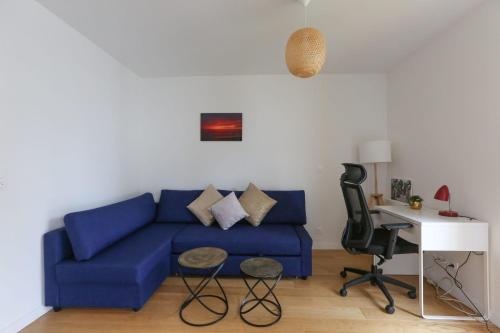 - un canapé bleu dans le salon avec un bureau dans l'établissement Cozy 60 m on the outskirts of Paris, à Gentilly