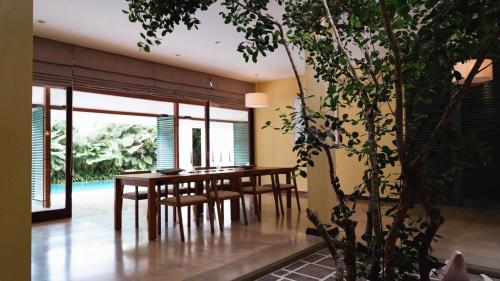 a dining room with a table and chairs and a tree at The Bloom Saffron in Negombo