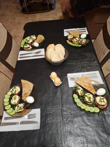 a table topped with plates of sandwiches and vegetables at Guesthouse different in Tbilisi City