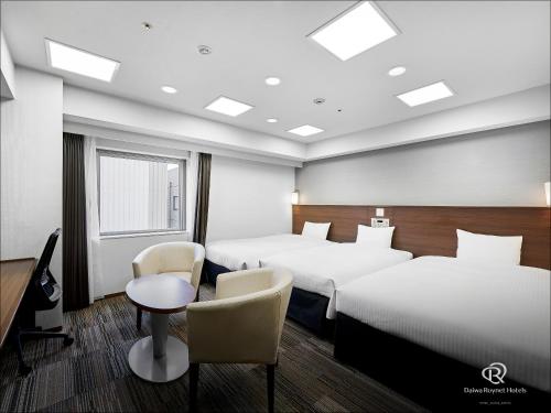 a hotel room with two beds and a table and chairs at Daiwa Roynet Hotel Sendai in Sendai