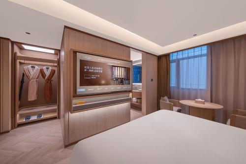 上海Crystal Orange Hotel Shanghai International Tourism Resort Pudong Airport的一间带大电视的卧室和一间更衣室