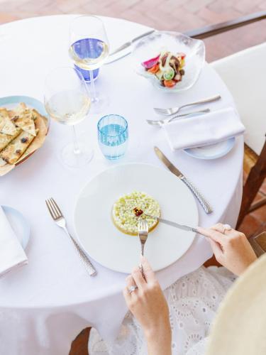 a woman sitting at a table with a plate of food at Hotel Pitrizza, Costa Smeralda in Porto Cervo