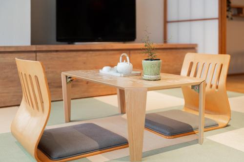 a wooden table with two chairs and a table with a plant on it at Solvana Akasaka in Tokyo