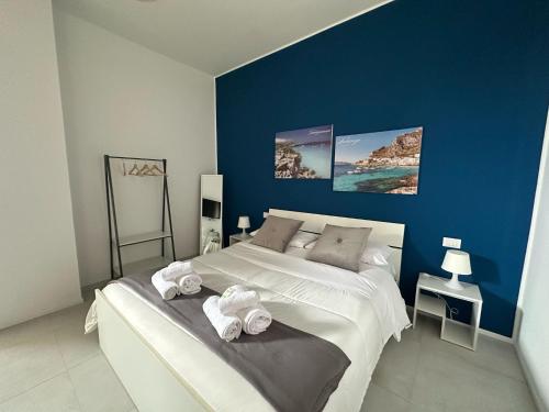 a bedroom with a large white bed with blue walls at Blu Eracleo in Trapani