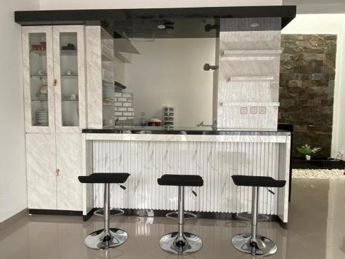 a kitchen with three bar stools in front of a counter at De Haus Villa Syariah Sukabumi in Krawang