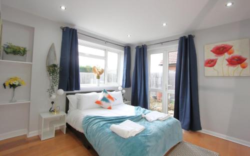 a bedroom with a bed with blue curtains and a window at Stunning 3 Bedroom 2 Bathroom Bungalow by CozyNest in Earley