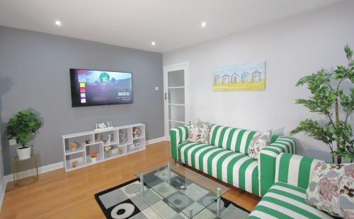 a living room with two green couches and a flat screen tv at Stunning 3 Bedroom 2 Bathroom Bungalow by CozyNest in Earley