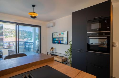 Il comprend un salon avec une cuisine équipée d'une table et d'un four micro-ondes. dans l'établissement Charmant T2 proche centre ville et terrasse, à Propriano