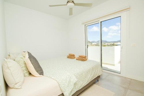 a white bedroom with a bed and a window at Casa Carann - By AZ Rentals in Uga