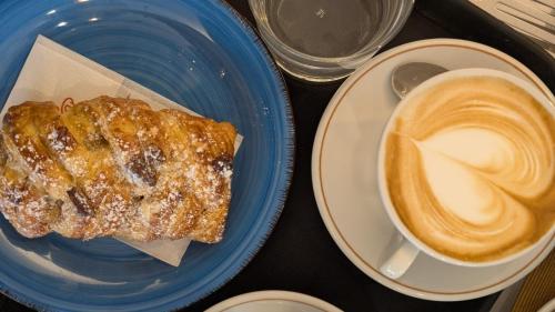 un piatto blu con un pezzo di pane e una tazza di caffè di B&B Rosmini-appartamento a Rovereto