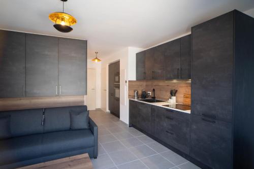 une cuisine avec des placards noirs et un canapé bleu dans l'établissement Studio moderne et lumineux, proche centre ville, à Propriano