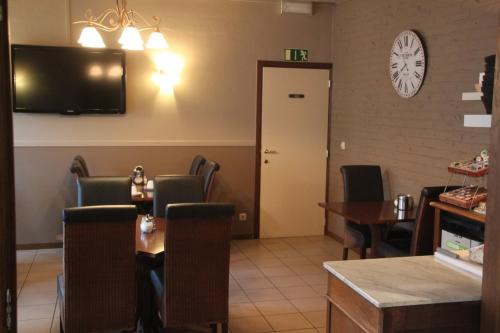Hotel Lommel Broek في Kerkhoven: غرفة طعام مع طاولة وكراسي وتلفزيون