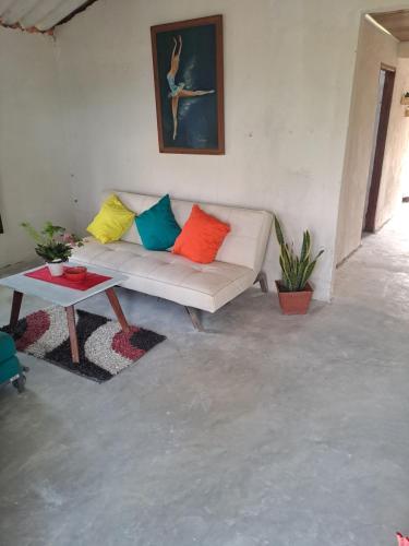 a living room with a white couch with colorful pillows at Apart Cabaña KTIK in San Bernardo del Viento