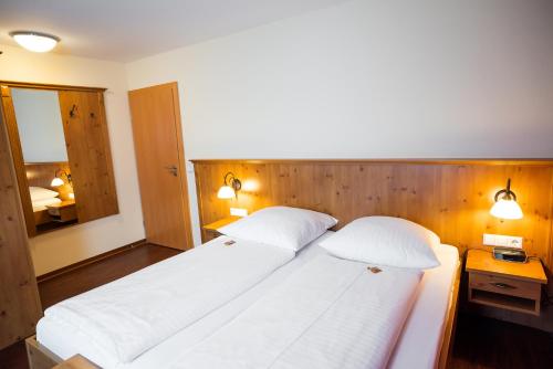 a bedroom with two white beds and a wooden headboard at Landgasthof Linde - In ruhiger, ländlicher Umgebung in Deggenhausertal