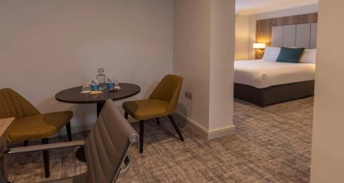 a hotel room with a bed and a table and chairs at Crowne Plaza East Midlands Airport by IHG in Derby