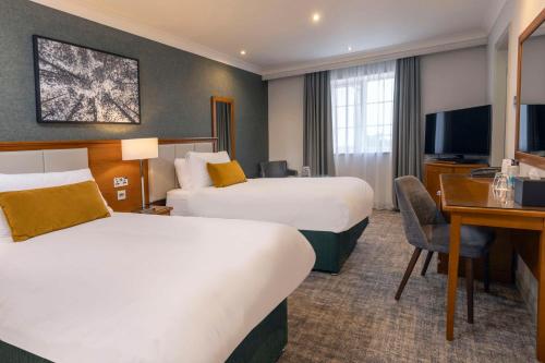 a hotel room with two beds and a desk at Crowne Plaza East Midlands Airport by IHG in Derby