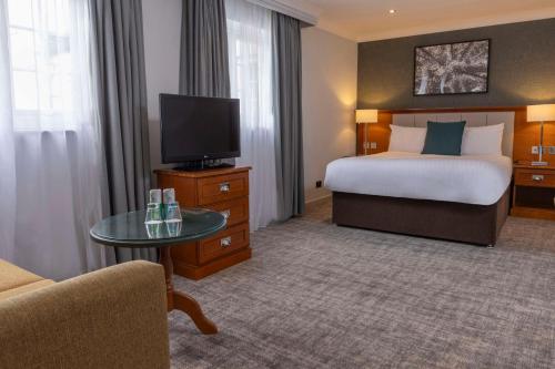 a hotel room with a bed and a flat screen tv at Crowne Plaza East Midlands Airport by IHG in Derby