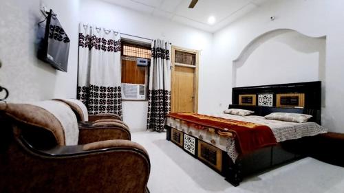 a bedroom with two beds and a couch and a tv at Hotel Lord #krishna Home Stay in Mathura