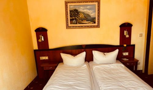 two beds in a room with a picture on the wall at Hotel Ostseeblick - direkt hinter den Dünen in Ostseebad Karlshagen