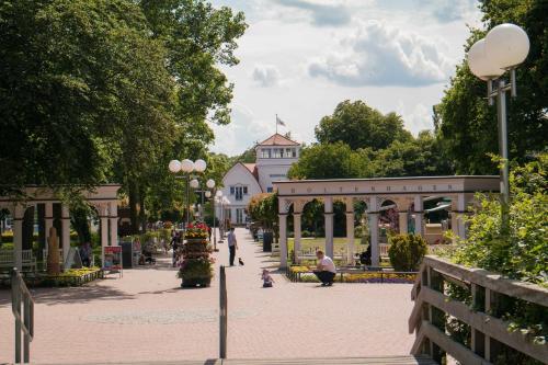 ein Park mit Menschen, die auf einem Bürgersteig sitzen, und einem Gebäude in der Unterkunft Residenz Düne III - Ferien-Apartments in Boltenhagen in Boltenhagen
