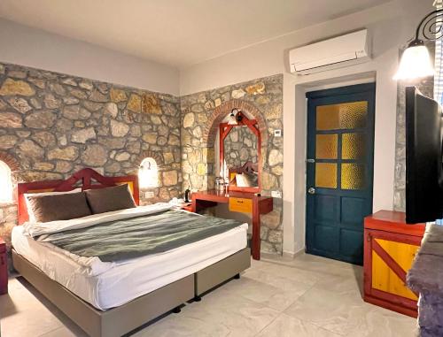 a bedroom with a bed and a stone wall at Symbola Oludeniz Beach Hotel in Oludeniz
