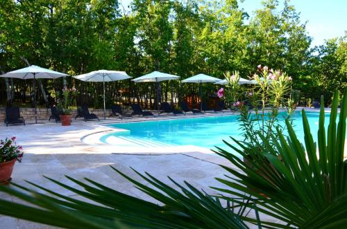 a swimming pool with umbrellas and chairs at Le Clos des Capitelles in Saint-Privat-de-Champclos