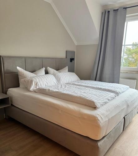 a bedroom with a large white bed with a window at Hotel Ostseeblick - direkt hinter den Dünen in Ostseebad Karlshagen