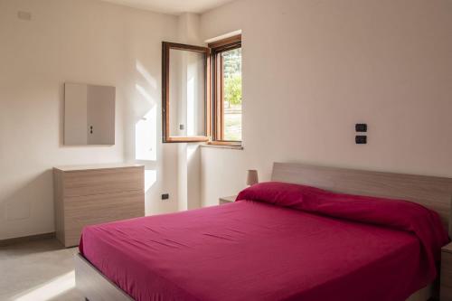 a bedroom with a red bed and a window at Villetta Luneria in Pisciotta