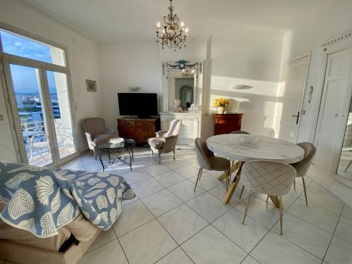un salon avec une table, des chaises et une télévision dans l'établissement Cannes Croisette - 2 pièces vue mer, à Cannes