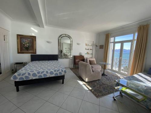 une chambre avec un lit, une chaise et un miroir dans l'établissement Cannes Croisette - 2 pièces vue mer, à Cannes