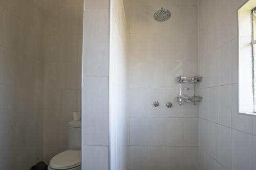 a white bathroom with a toilet and a shower at Montclair Resort & Conference in Nyanga