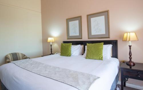a bedroom with a large white bed with green pillows at Montclair Resort & Conference in Nyanga