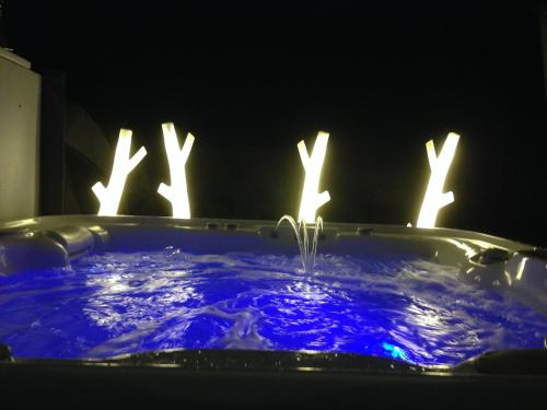 d'une baignoire éclairée avec de l'eau bleue et des lumières. dans l'établissement charmante maison avec jardin clos sur les dunes de Sainte Marguerite avec SPA en option, à Landéda