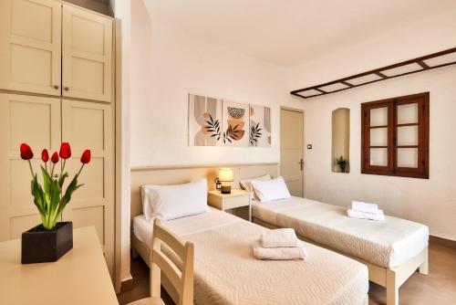 a room with two beds and a table with red tulips at Mila Malia Studios Hotel in Malia