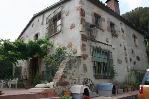 an old stone building with windows and a tree at MASIA CAN SUNYER AGROTURISMO in La Garriga