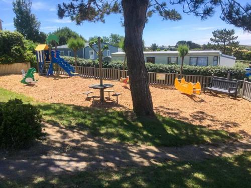 - une aire de jeux avec un arbre et une balançoire dans l'établissement Camping Paradis La Mer d'Iroise - Aquatique Vacances, à Plomodiern