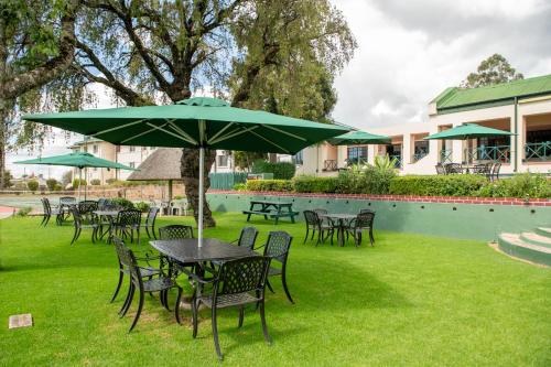 a group of tables and chairs with a green umbrella at Montclair Resort & Conference in Nyanga