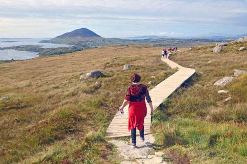 a woman walking along a wooden path on a hill at Cottage 484 - Moyard in Moyard