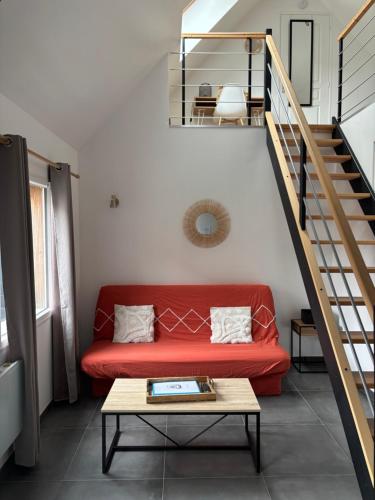 - un canapé rouge dans le salon avec un escalier dans l'établissement La Hulotte 2 - Sur la route du Mont-St-Michel, à Céaux