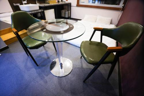 a glass table and two green chairs in a room at Seomyeon X in Busan