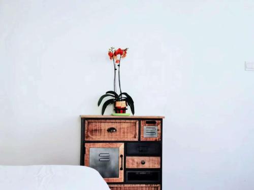 a dresser with a vase of flowers on top of it at 淳安千岛湖乡庐怡陌民宿 in Thousand Island Lake