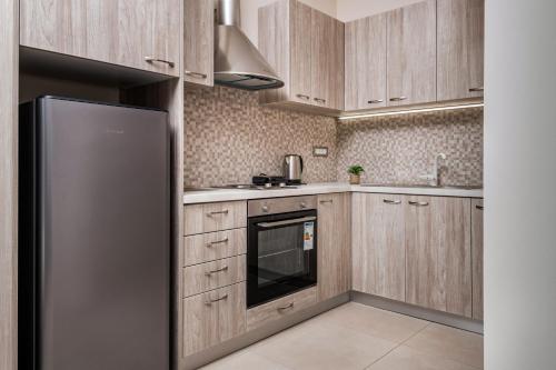 eine Küche mit Holzschränken und einem Kühlschrank aus Edelstahl in der Unterkunft Katsaros Luxury Apts 5 min walk to beach in Planos