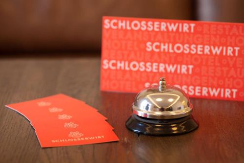 a bell sitting on a table next to a red card at Hotel & Boarding House Schlosserwirt in Mering