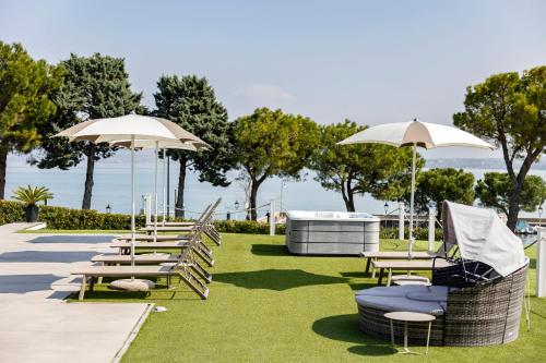 a row of chairs and umbrellas on the grass at Vision Hotel in Peschiera del Garda