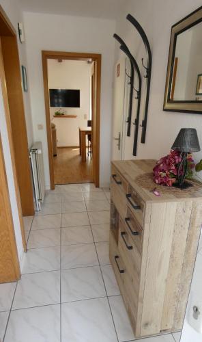 a kitchen with a wooden chest of drawers and a hallway at Haus Sarah in Dornum