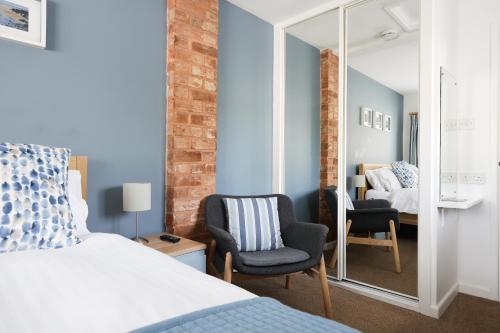 a bedroom with a bed and two chairs and a mirror at Berwick House in Sidmouth