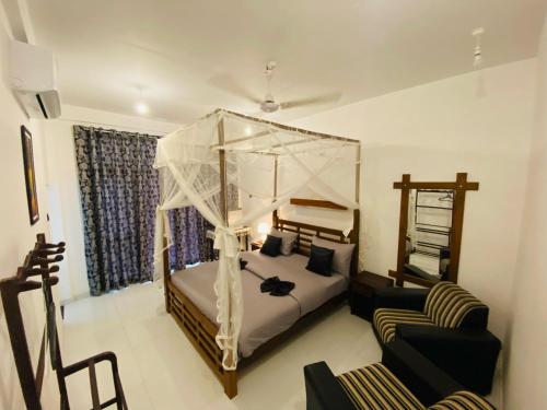 a bedroom with a canopy bed and a couch at Sigiri Holiday Bungalow in Sigiriya