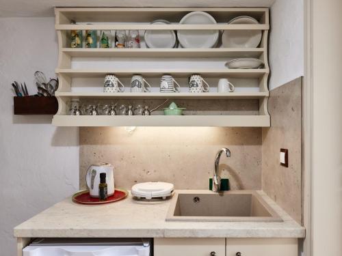 a kitchen with a sink and shelves with dishes at Mila Malia Studios Hotel in Malia
