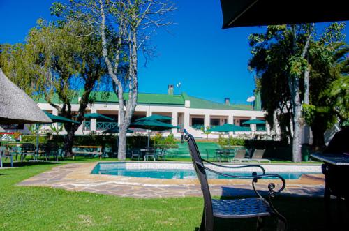 a pool with chairs and umbrellas in front of a building at Montclair Resort & Conference in Nyanga